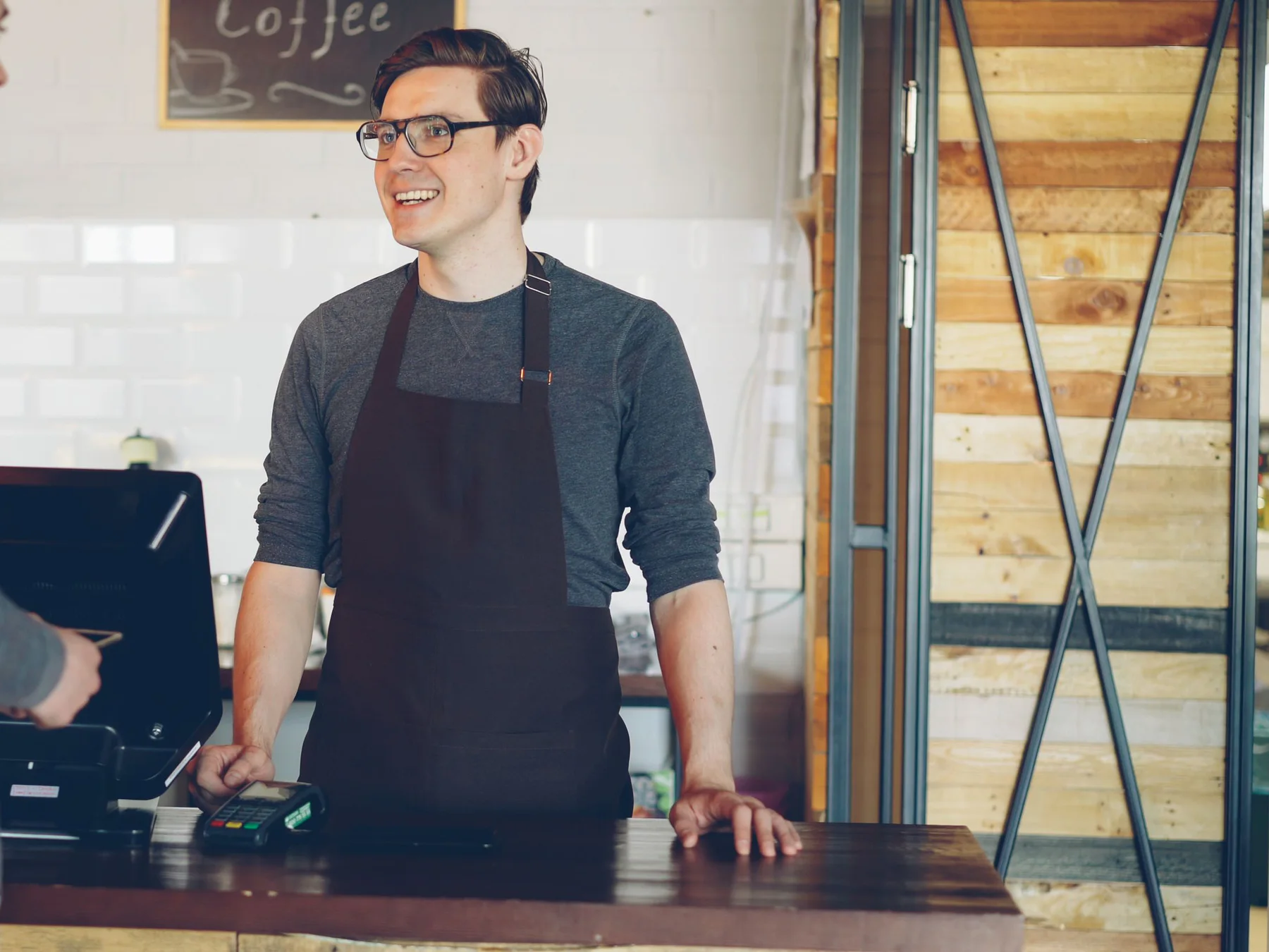 Un barista atén clients a la barra d'una cafeteria