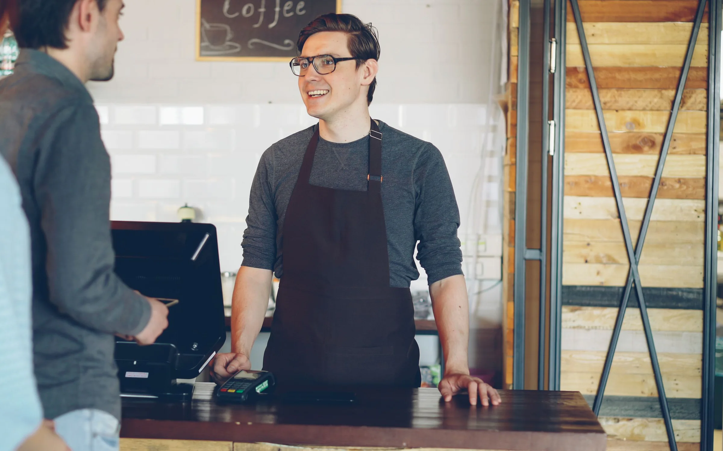 Un barista atén clients a la barra d'una cafeteria