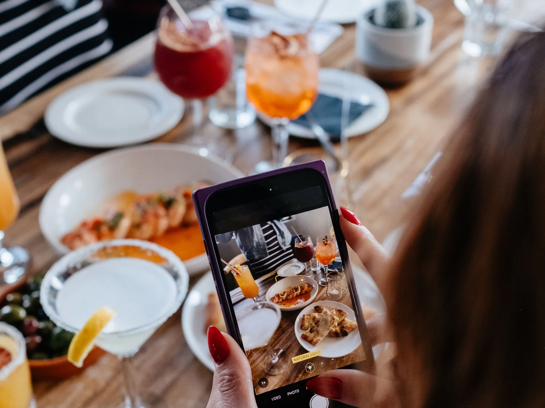 Una comensal fa servir el telèfon al costat de plats per compartir