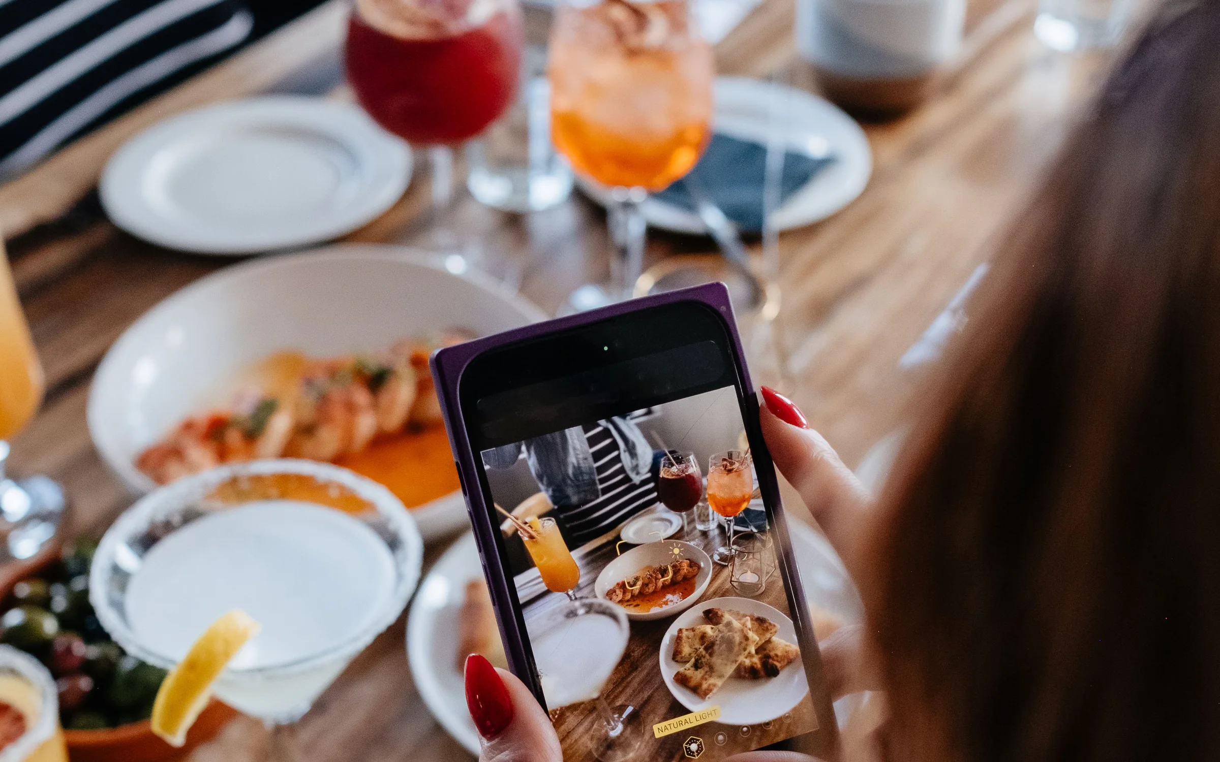 Una comensal fa servir el telèfon al costat de plats per compartir